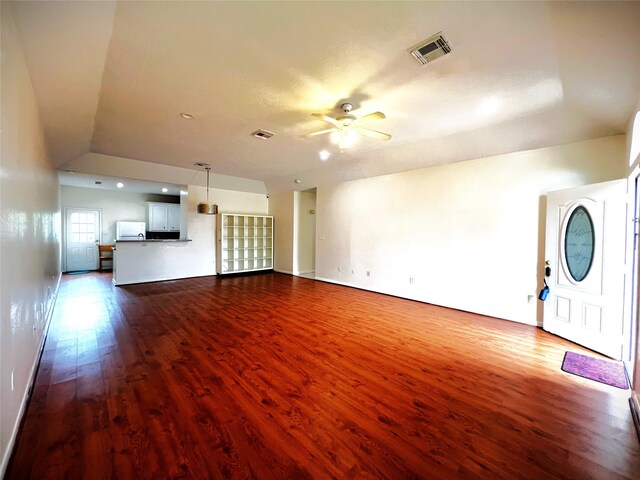 unfurnished living room with visible vents, baseboards, dark wood-type flooring, and ceiling fan