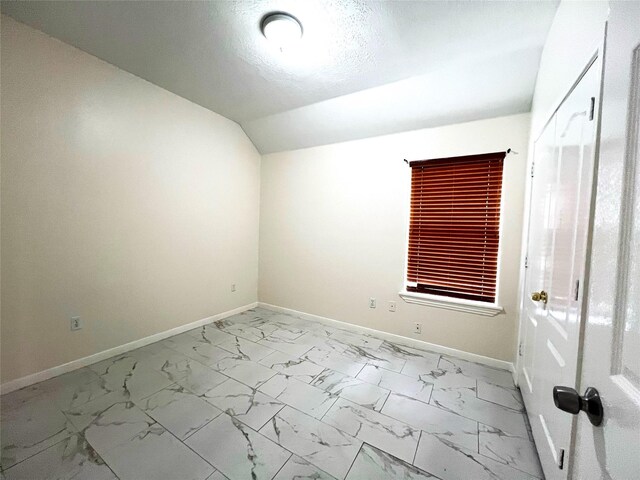 interior space featuring baseboards, lofted ceiling, a textured ceiling, and marble finish floor