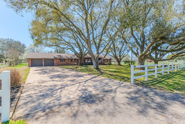 view of front of property with a front yard, concrete driveway, a garage, a fenced front yard, and brick siding