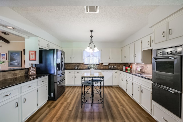 kitchen featuring dark countertops, visible vents, oven, dishwasher, and stainless steel refrigerator with ice dispenser