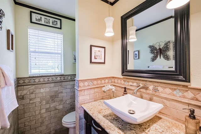 bathroom with tile walls, a wainscoted wall, toilet, and vanity