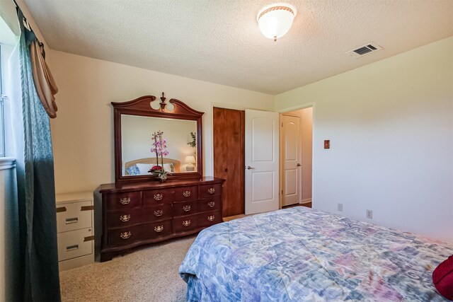 carpeted bedroom featuring a closet, visible vents, and a textured ceiling