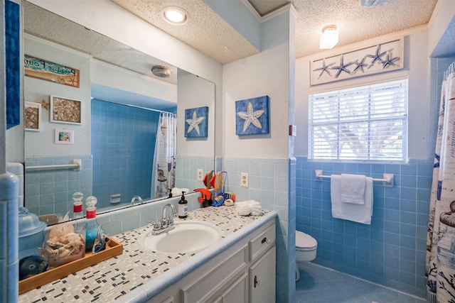 full bath featuring a textured ceiling, tile patterned flooring, wainscoting, tile walls, and toilet