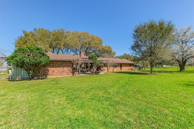 back of property featuring brick siding, a lawn, and a patio area