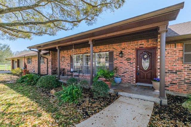 entrance to property featuring brick siding and a porch