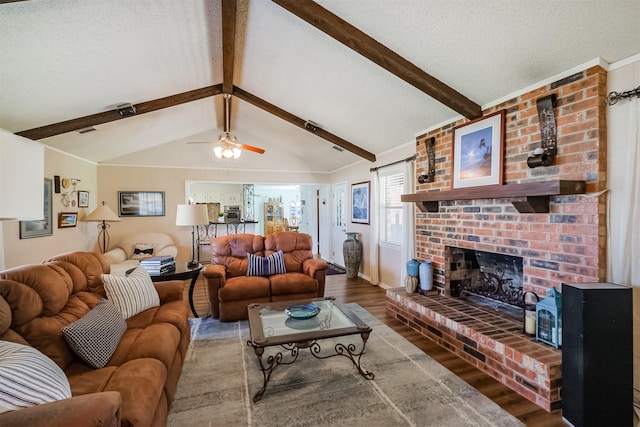 living room with a textured ceiling, wood finished floors, a fireplace, baseboards, and vaulted ceiling with beams