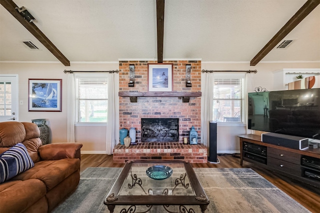 living room featuring visible vents, beam ceiling, a brick fireplace, and wood finished floors