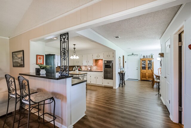 kitchen featuring a kitchen breakfast bar, dark wood finished floors, white cabinetry, appliances with stainless steel finishes, and a peninsula