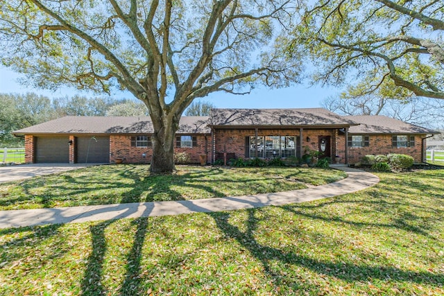 single story home featuring a garage, driveway, brick siding, and a front yard