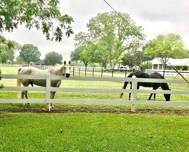 view of gate featuring a rural view, a lawn, and fence