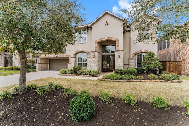 view of front of home featuring fence, driveway, stucco siding, french doors, and stone siding