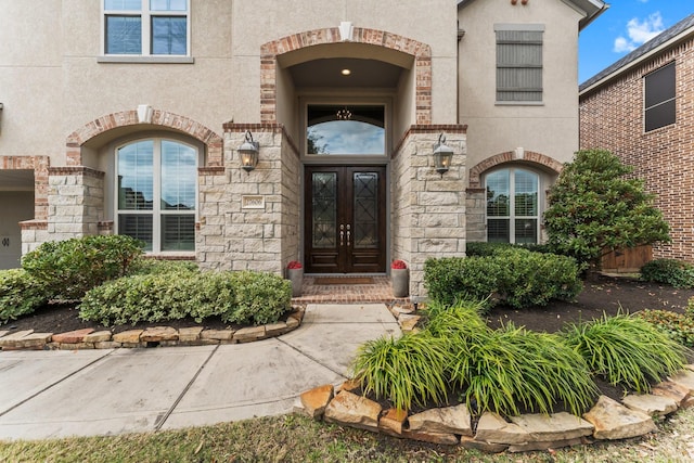 property entrance featuring french doors, stone siding, and stucco siding