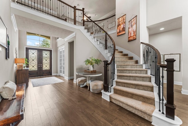 foyer entrance featuring stairway, wood finished floors, baseboards, french doors, and a towering ceiling