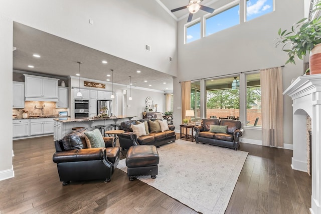 living room with visible vents, dark wood-type flooring, a healthy amount of sunlight, and a ceiling fan