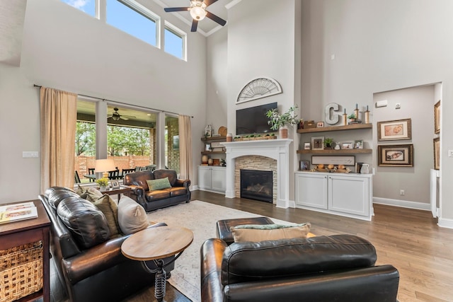 living room featuring ceiling fan, baseboards, wood finished floors, and a fireplace