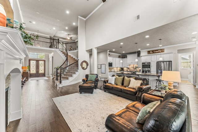 living room with french doors, dark wood-style flooring, stairs, and crown molding