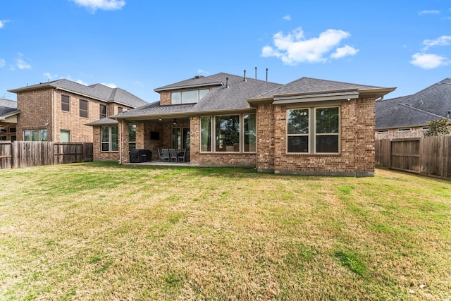 back of property featuring a yard, brick siding, a fenced backyard, and a patio area