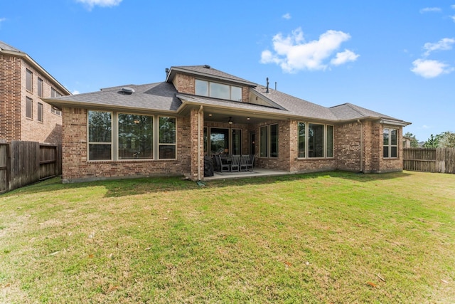 rear view of house featuring brick siding, a yard, a fenced backyard, a patio area, and a ceiling fan