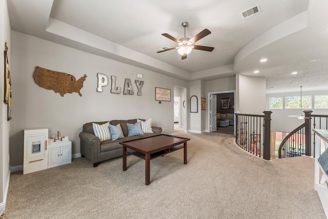 living room featuring a tray ceiling, recessed lighting, baseboards, light colored carpet, and ceiling fan