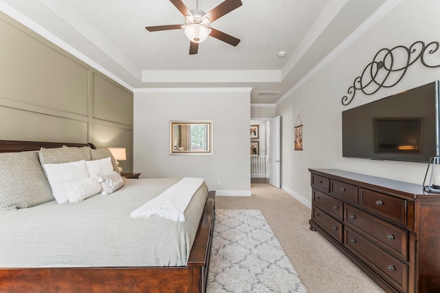 bedroom featuring baseboards, a tray ceiling, ceiling fan, light carpet, and a decorative wall