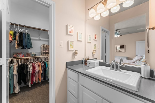 bathroom featuring a walk in closet, ceiling fan, and vanity