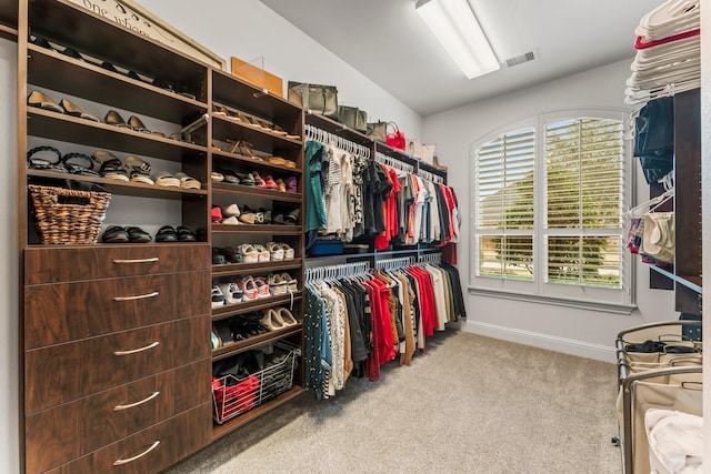 walk in closet with visible vents, lofted ceiling, and carpet