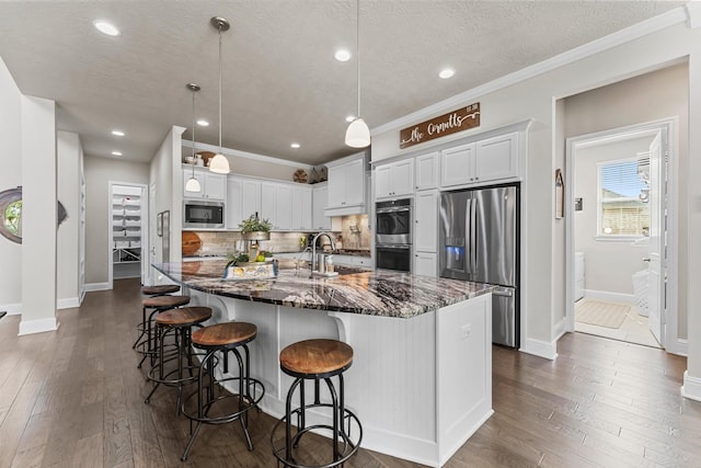 kitchen featuring tasteful backsplash, dark wood-style flooring, a large island with sink, and stainless steel appliances