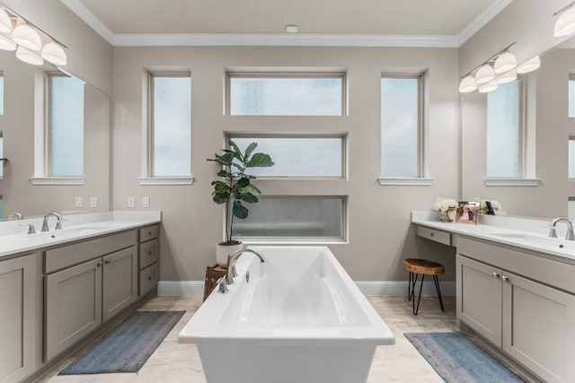 bathroom featuring crown molding, a soaking tub, two vanities, and a sink