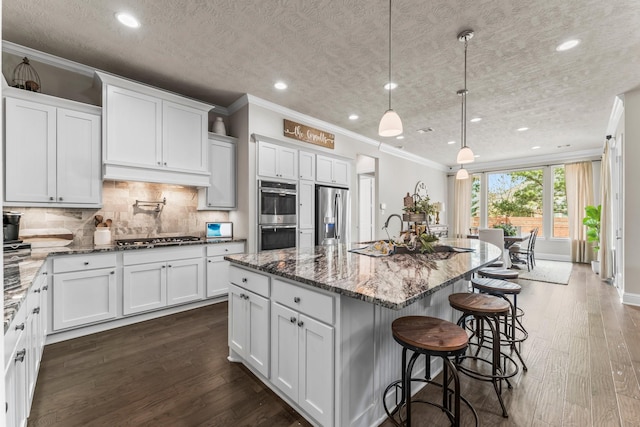 kitchen with backsplash, appliances with stainless steel finishes, ornamental molding, and white cabinets