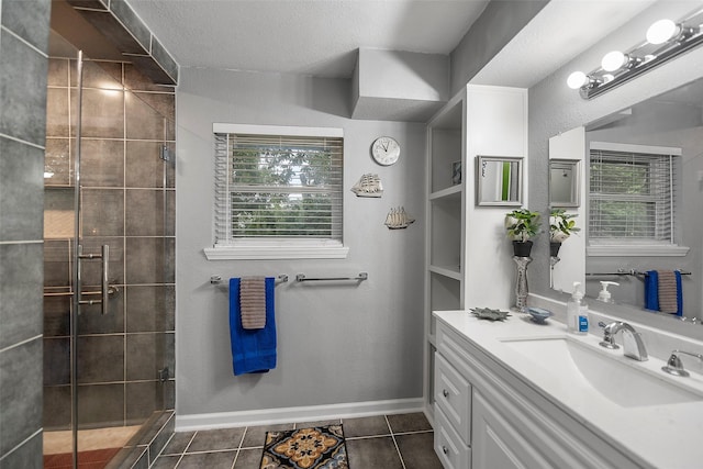 full bathroom featuring tile patterned flooring, baseboards, vanity, a tile shower, and a textured ceiling