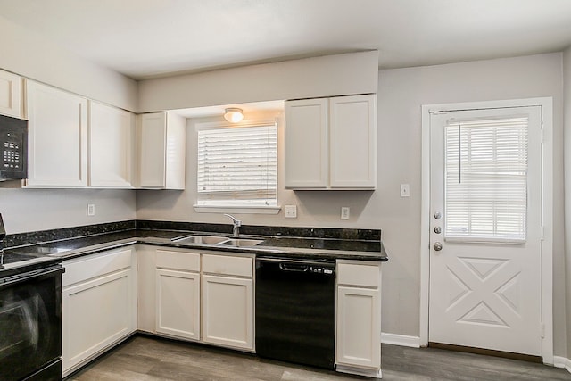 kitchen with white cabinetry, black appliances, wood finished floors, and a sink