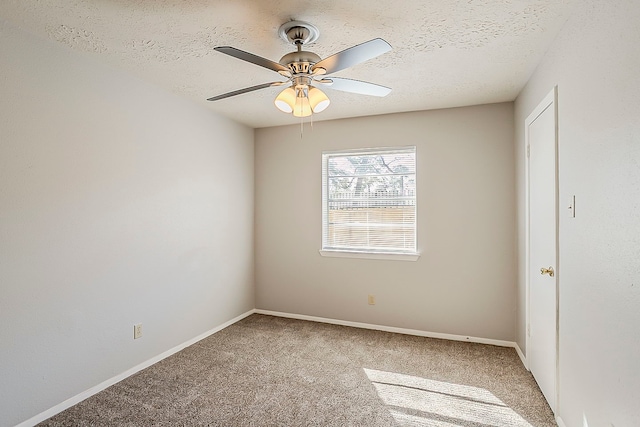 spare room with light carpet, a textured ceiling, baseboards, and a ceiling fan