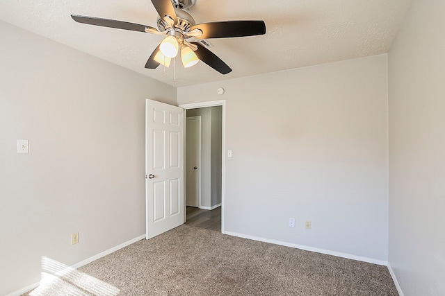 spare room with carpet, baseboards, and a textured ceiling