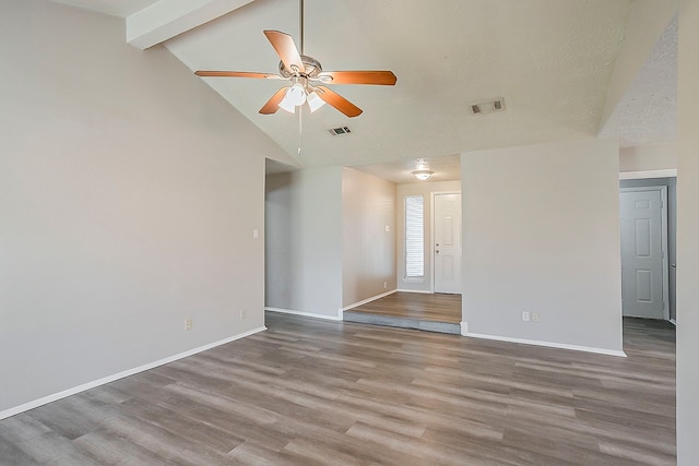 spare room with vaulted ceiling with beams, wood finished floors, visible vents, and baseboards