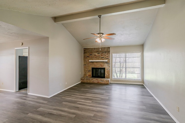 unfurnished living room featuring wood finished floors, vaulted ceiling with beams, ceiling fan, a textured ceiling, and a brick fireplace