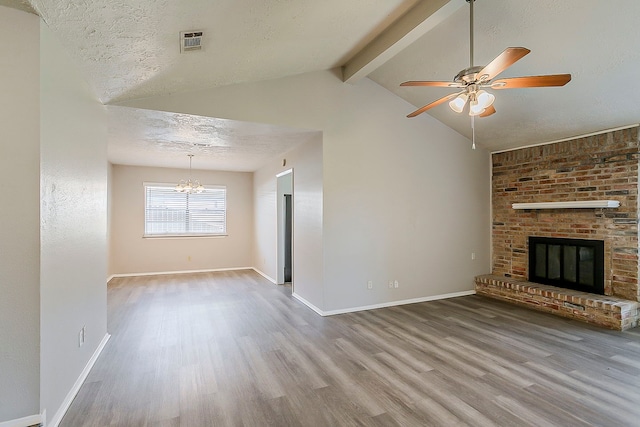 unfurnished living room with wood finished floors, visible vents, lofted ceiling with beams, a textured ceiling, and a brick fireplace