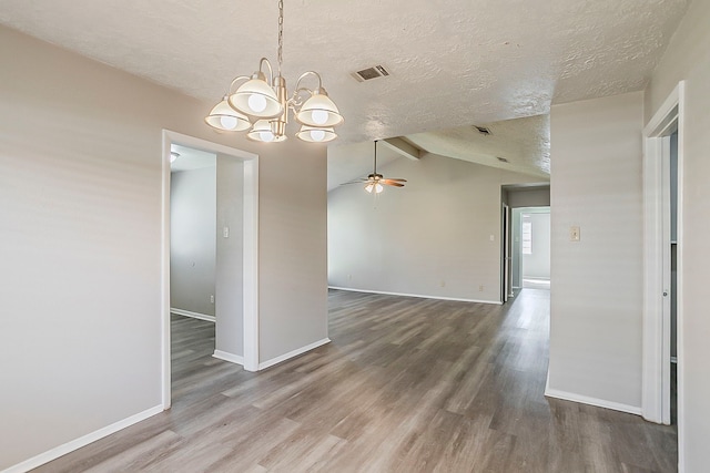 spare room featuring visible vents, a textured ceiling, wood finished floors, baseboards, and vaulted ceiling with beams