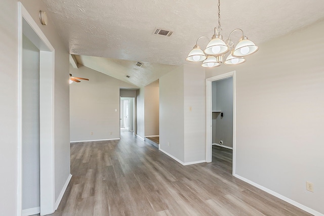 unfurnished room featuring visible vents, baseboards, lofted ceiling, wood finished floors, and a textured ceiling