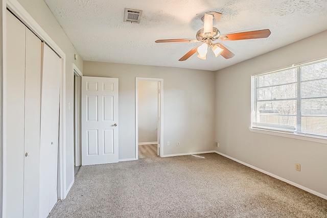 unfurnished bedroom with visible vents, light carpet, a textured ceiling, a closet, and baseboards