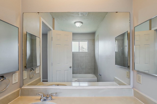 full bathroom featuring visible vents, a textured ceiling, shower / tub combination, and a sink