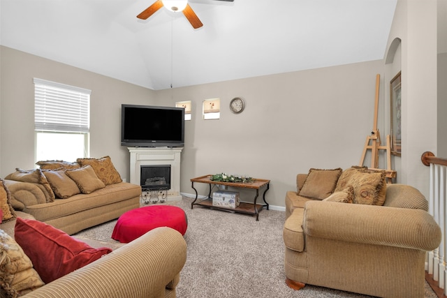 living area featuring a ceiling fan, carpet floors, a fireplace, baseboards, and vaulted ceiling