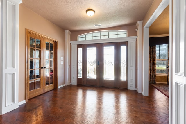 foyer with visible vents, dark wood-type flooring, a textured ceiling, french doors, and baseboards