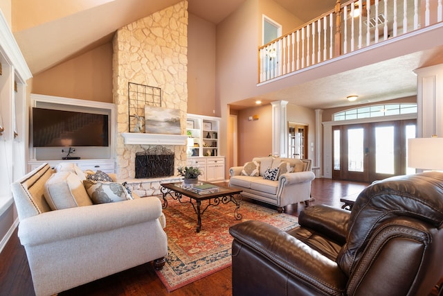 living area with a fireplace, wood finished floors, ornate columns, and high vaulted ceiling