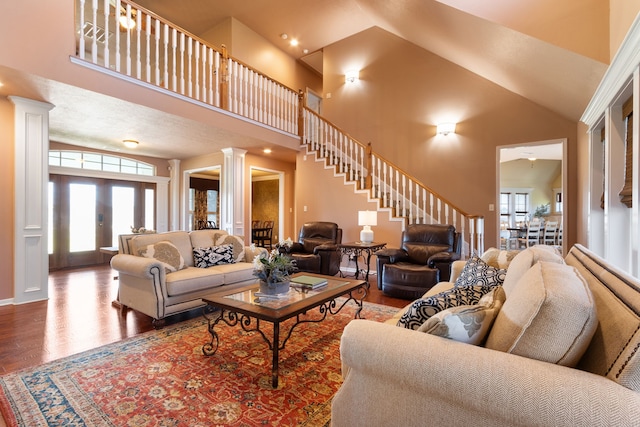 living room featuring stairs, wood finished floors, a healthy amount of sunlight, and ornate columns