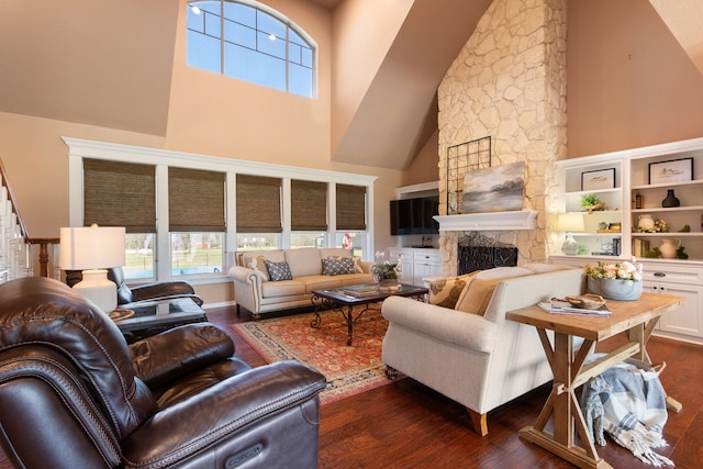 living area featuring a stone fireplace, a high ceiling, and dark wood-style flooring