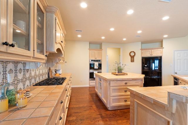 kitchen with dark wood-style floors, a kitchen island, decorative backsplash, black appliances, and tile counters