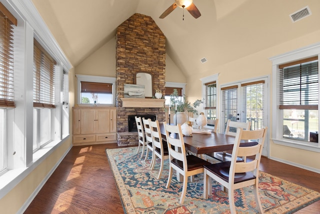 dining space featuring visible vents, a stone fireplace, wood finished floors, and a ceiling fan