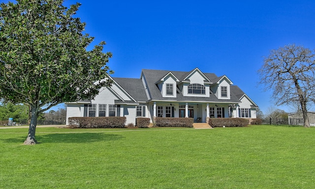 new england style home featuring covered porch, a front yard, and fence