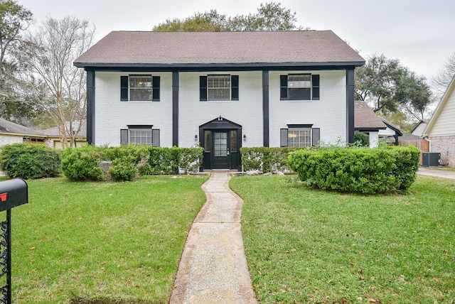 view of front of property with a front lawn, central air condition unit, and brick siding