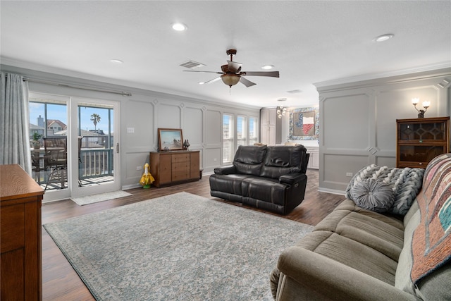 living area featuring visible vents, dark wood-style floors, crown molding, and a decorative wall